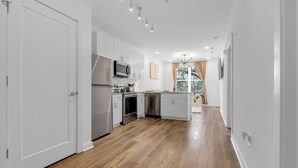 Una cucina moderna con mobili bianchi, elettrodomestici in acciaio inossidabile e pavimento in legno.