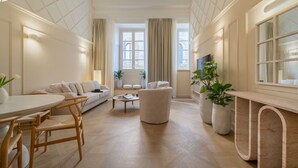 Amplia sala de estar con un sofá, sillones, una mesa de centro y un comedor con sillas y una mesa.