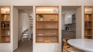 Un interior moderno con estanterías de madera integradas, un comedor con mesa redonda y una cocina con encimeras de mármol.