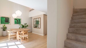 Ein geräumiges Zimmer mit einem Holzesstisch, Stühlen und einer Treppe.