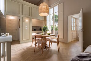 Une cuisine moderne avec un coin repas, comprenant une table ronde en bois, des chaises et un luminaire suspendu.