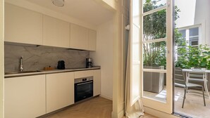 A modern kitchen with a marble backsplash, built-in dishwasher, and a sliding glass door leading to a balcony with outdoor furniture.