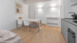 Une cuisine compacte avec un coin repas, une porte blanche et une petite table avec des chaises.