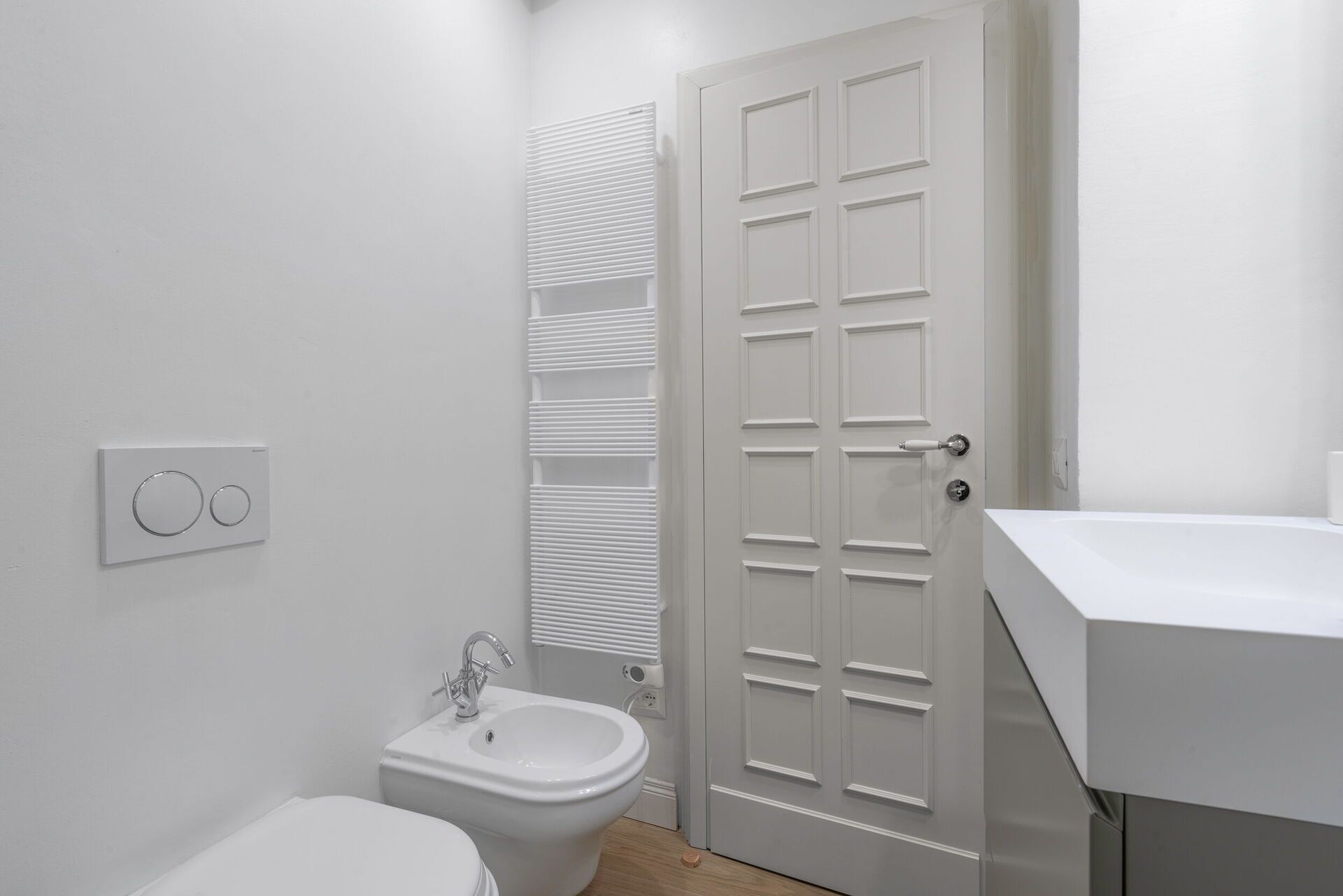 A bathroom with a toilet, bidet, and a white sink.