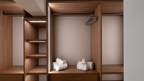 Een houten garderobe met verschillende planken en lades, inclusief een kledingroede en netjes opgevouwen handdoeken.