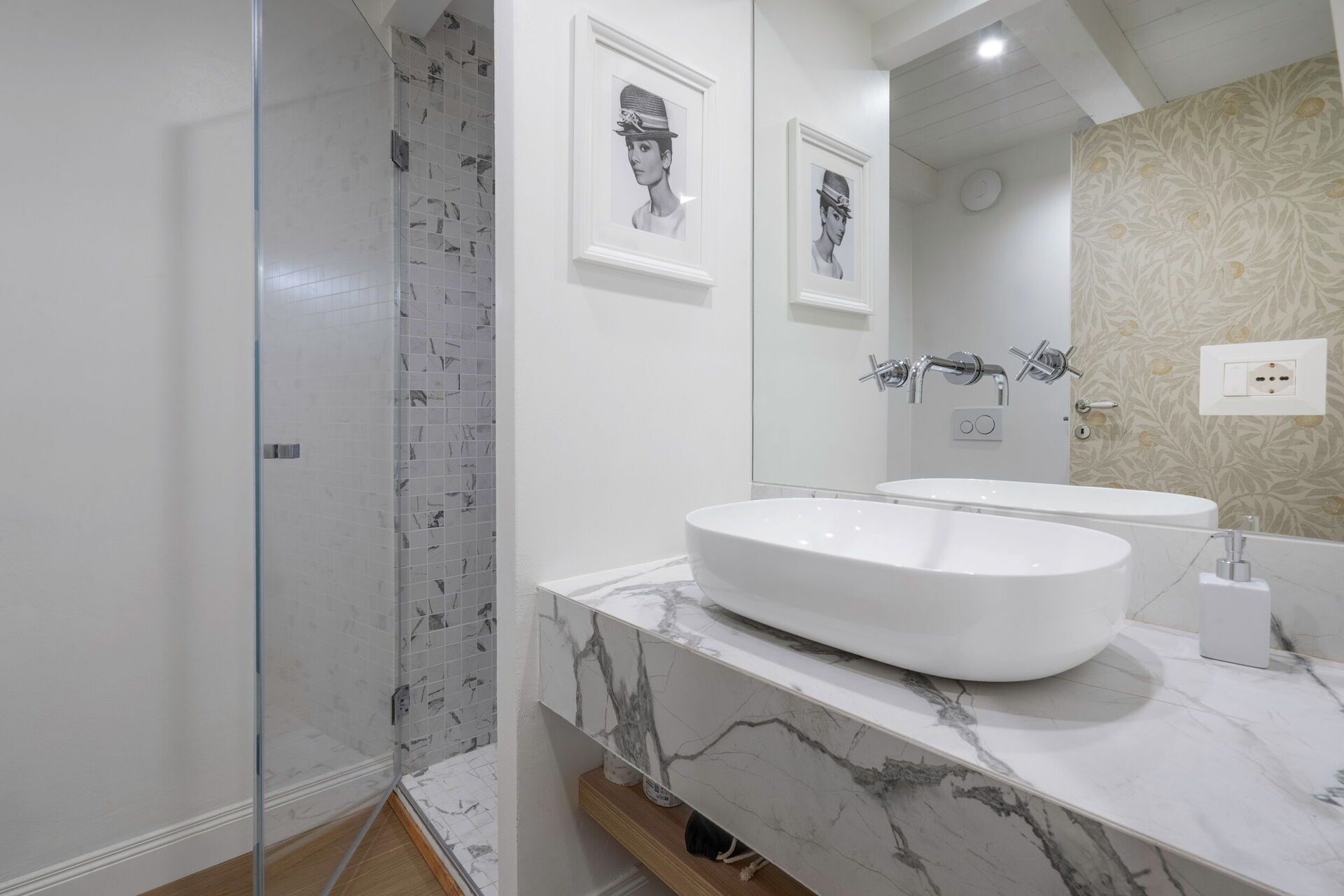 A modern bathroom with a glass shower enclosure, a large oval sink, and a mirror above the sink.