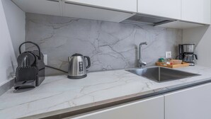 A modern kitchen with a marble backsplash, a kettle, a coffee maker, and a sink. - Deservi Elegant Apt. Dante (Florence)