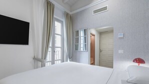 A hotel room with a large bed, a window with curtains, a door leading to a bathroom, and a red lamp on a bedside table. - Deservi Elegant Apt. Dante (Florence)