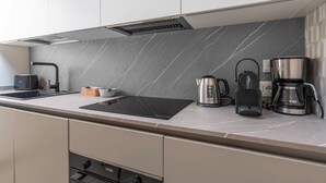 A modern kitchen with a sleek countertop, a built-in stove, a coffee maker, and a kettle.