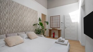 A modern bedroom with a large bed, a wooden bedside table, a wall-mounted TV, and a door with a geometric pattern.