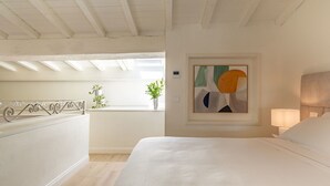 Een slaapkamer met een groot bed, een schilderij, een bedlampje en uitzicht op het balkon.
