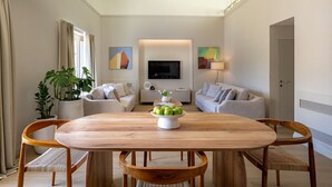 Een moderne woonkamer met een houten eettafel, twee banken, een televisie en een potplant.