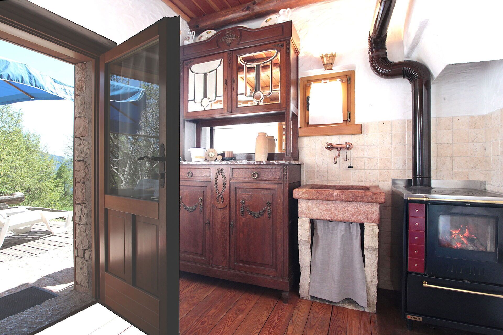 Una cucina rustica con mobili in legno, un piano di lavoro in pietra e una stufa a legna.