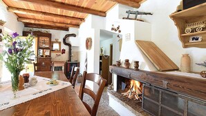 A rustic interior with a wooden dining table, chairs, a fireplace, and various decorative items.