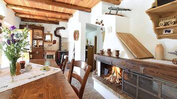 Un interno rustico con un tavolo da pranzo in legno, sedie, un camino e diversi oggetti decorativi.