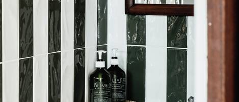 A bathroom with a white sink, a mirror, and two bottles of olive oil on the counter.