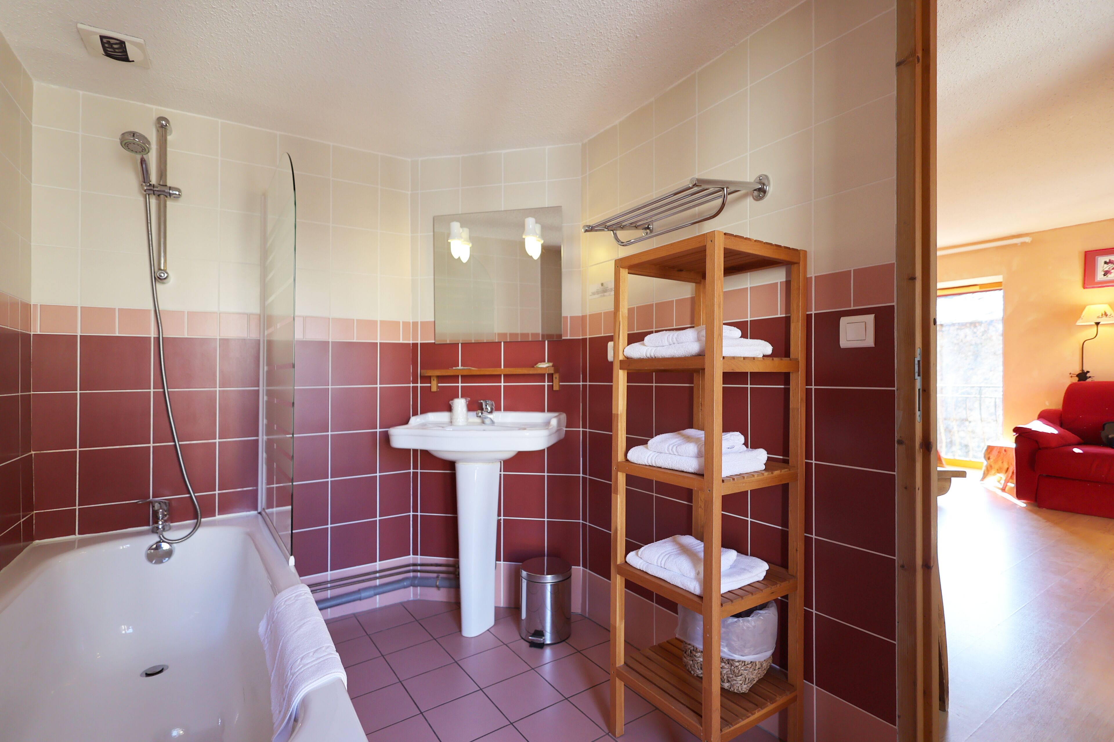 Ein Badezimmer mit Badewanne, Waschbecken, Spiegel und einem Ablagefach mit Handtüchern.