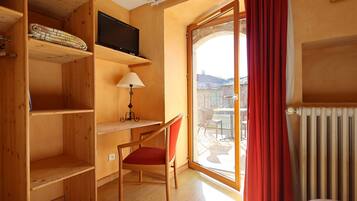 Una habitación con un escritorio de madera, una silla, un televisor y vistas a través de un ventanal.