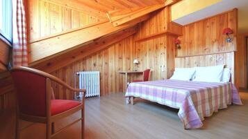 Une pièce en bois avec un lit, une chaise, une table et un radiateur.