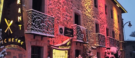 Un hotel de fachada de piedra, con señalización iluminada y paisajes nevados.
