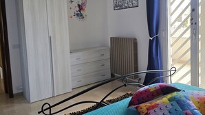 Une chambre à coucher avec un lit, une armoire, un radiateur et une fenêtre avec des rideaux.