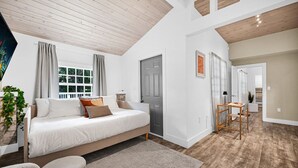 Une chambre spacieuse avec un grand lit, un plafond en bois et une vue sur le paysage urbain par la fenêtre.