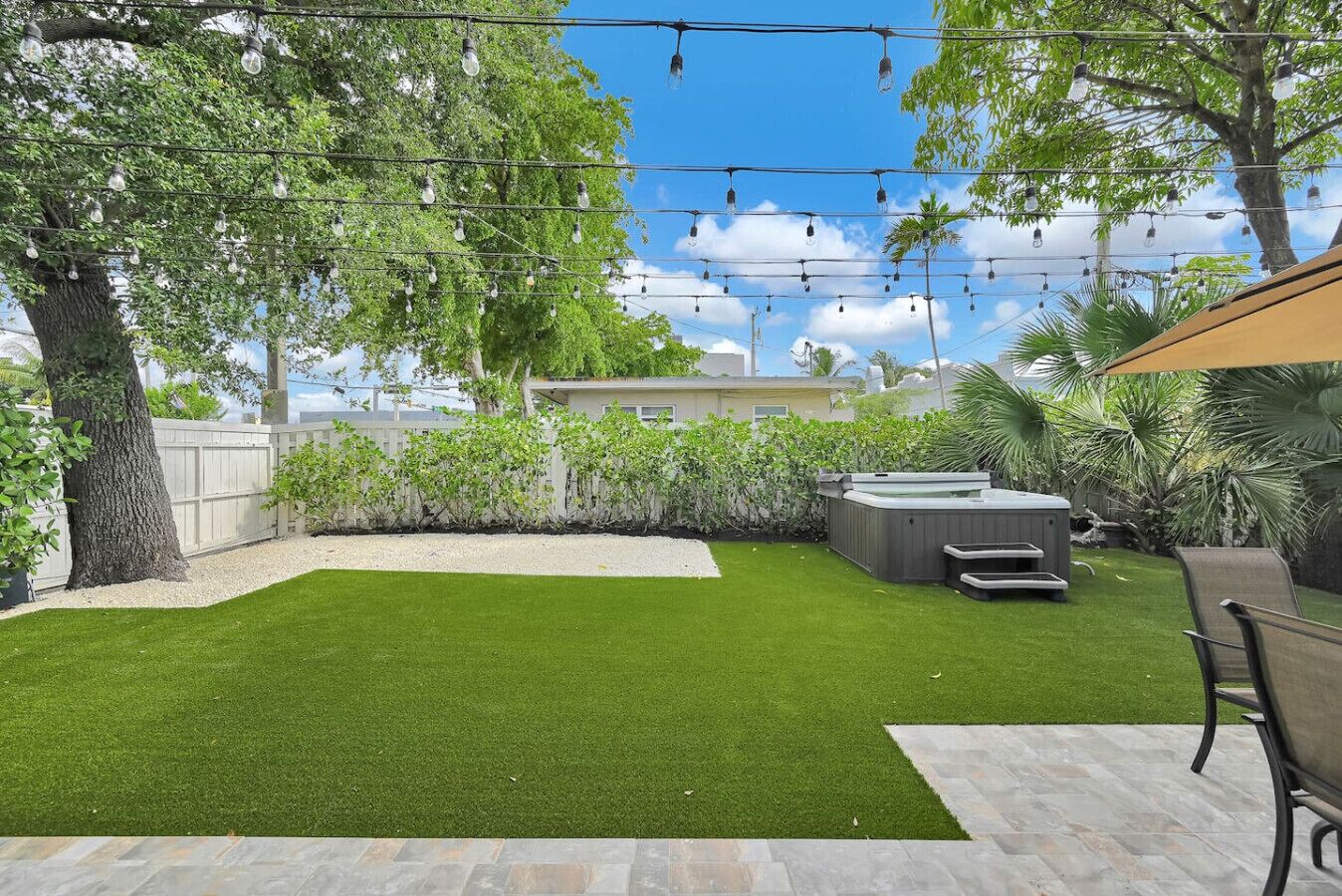 A backyard with artificial lighting, a hot tub, and a patio area.