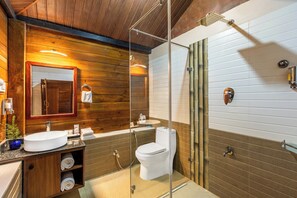 Un baño moderno con tocador de madera, cabina de ducha de vidrio y un inodoro blanco.