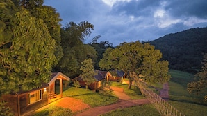 Un área de cabañas apartada, con varias cabañas de madera rodeadas de exuberante vegetación y un promontorio boscoso.