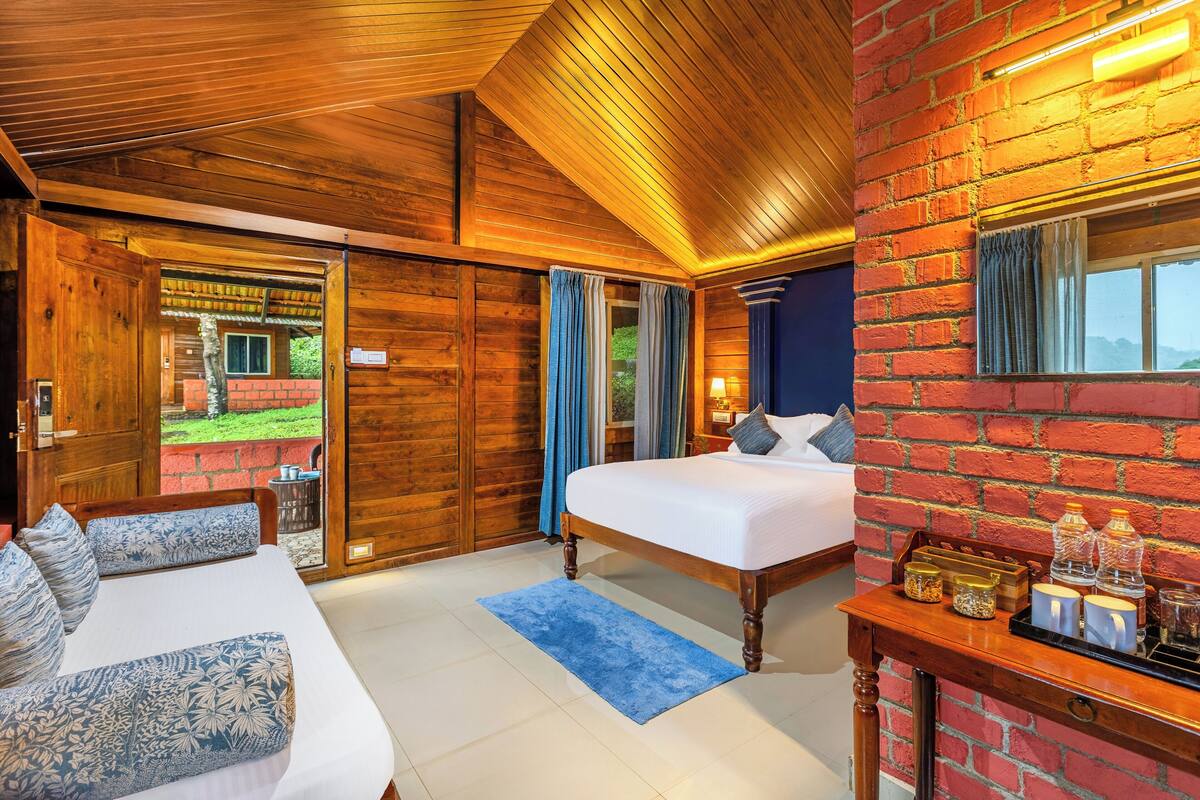 A wooden room with a bed, a sofa, and a table with candles.