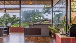 Un área de recepción con diseño moderno, que incluye un mostrador de recepción, zona de estar y grandes ventanales con vistas al paisaje circundante.