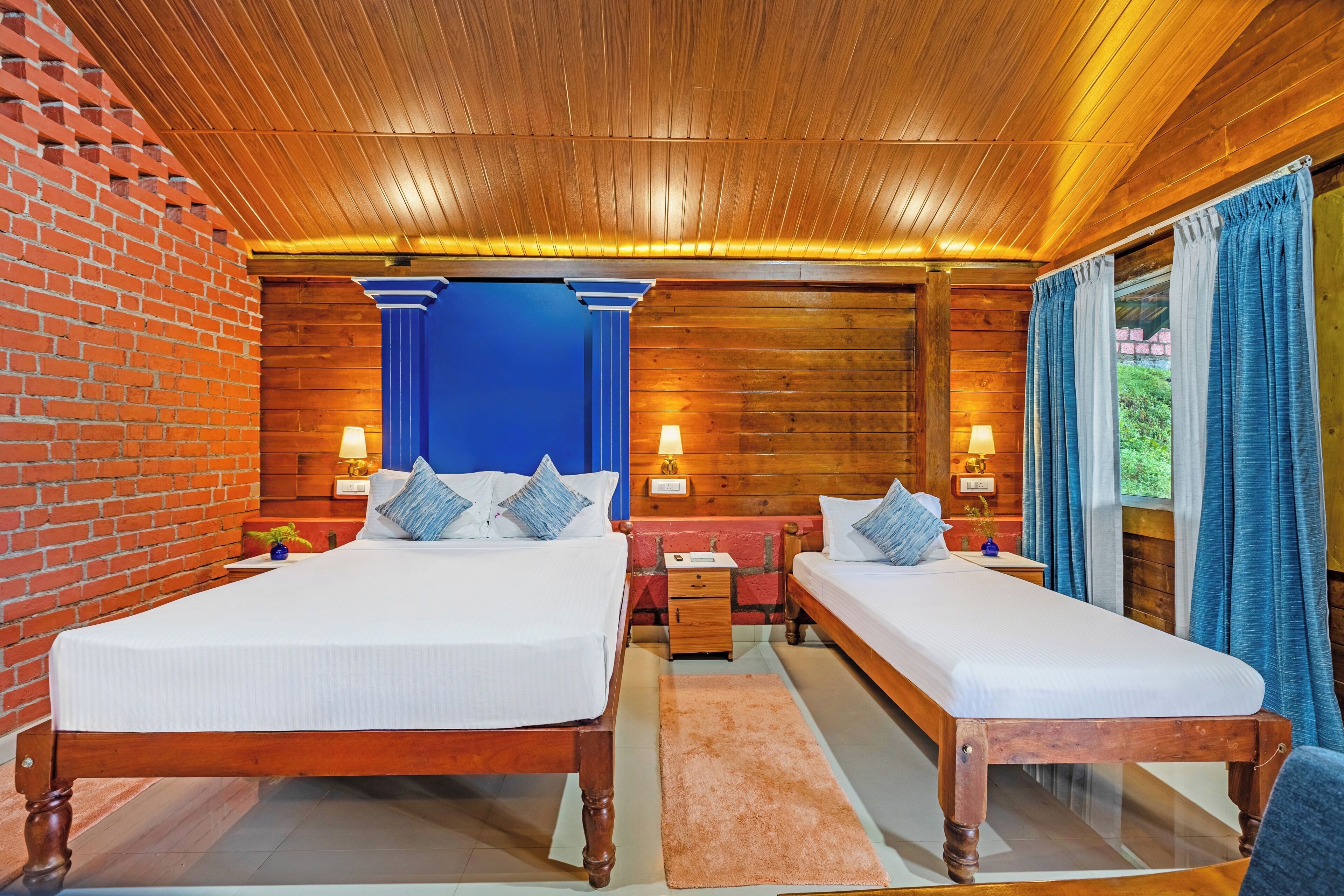 Ein Doppelzimmer mit zwei Betten, einer Ziegelwand, einer Holzbalkendecke und einer blauen Akzentwand.