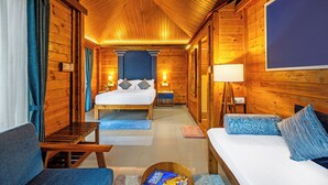 Una habitación de cabaña de madera con una cama, un sofá, una mesita y un escritorio con lámpara.
