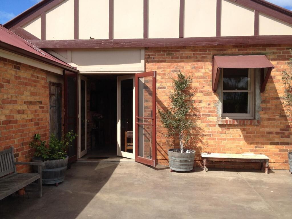 A building with a brick exterior, a wooden bench, a potted plant, and a sliding glass door.
