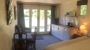 Une chambre d’hôtel comprenant un lit, une table à manger avec des chaises, un coin cuisine et une porte-fenêtre coulissante donnant sur un balcon.
