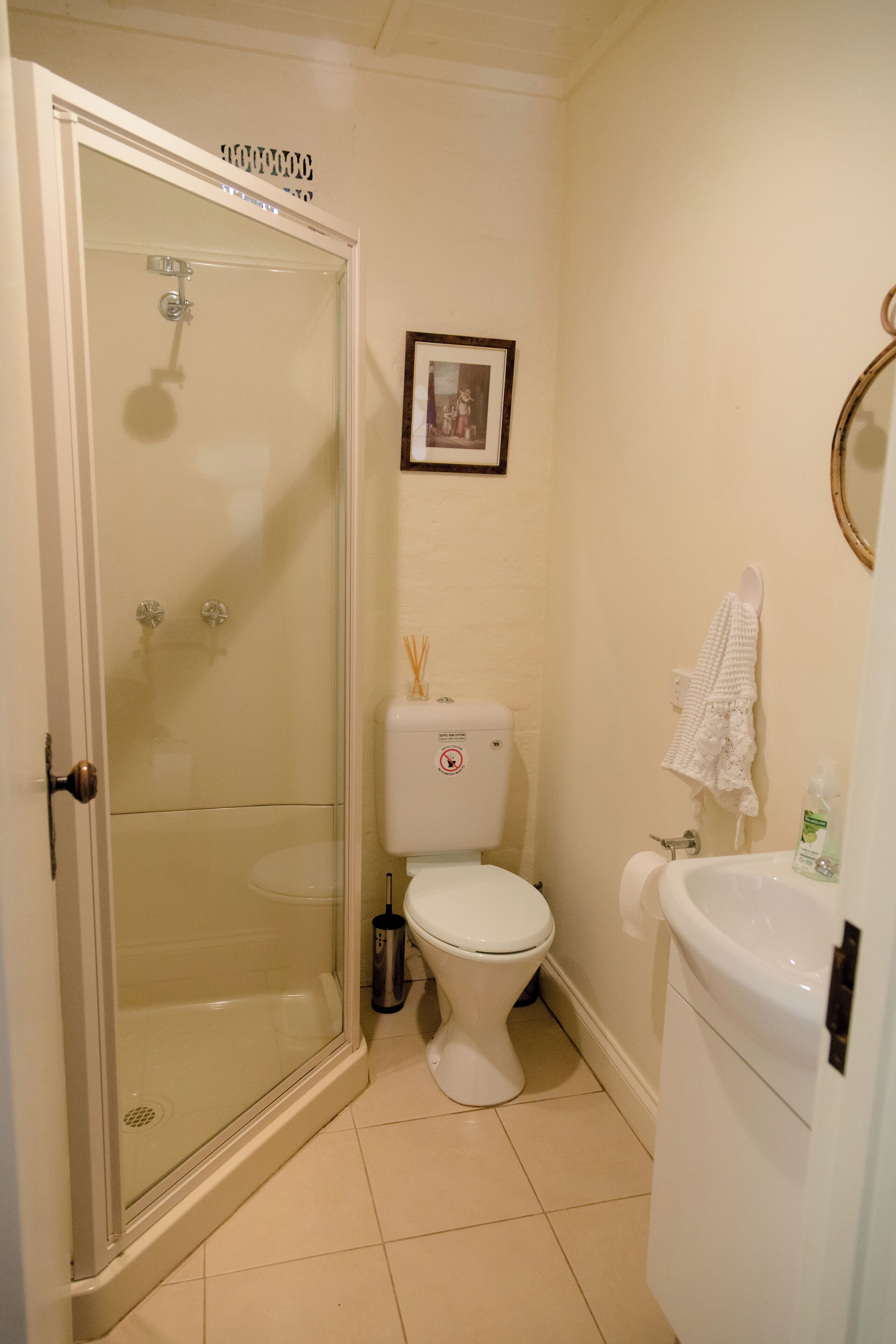 A bathroom with a glass-enclosed shower, a toilet, and a sink.