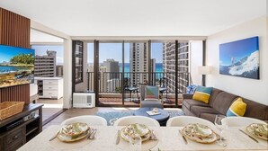 Ein modernes Wohnzimmer mit Essbereich, großen Fenstern und Stadtblick sowie einem Balkon mit Sitzgelegenheit.