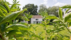 A house with a red-tiled roof, surrounded by lush greenery and trees. - Charming 2-bedroom villa in brilliant Merelbeke-Melle with AC (Merelbeke-Melle)