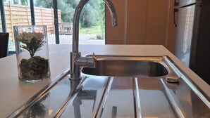 A modern kitchen with a stainless steel sink, a glass vase with flowers, and a view of the outdoors through large windows. - Charming 2-bedroom villa in brilliant Merelbeke-Melle with AC (Merelbeke-Melle)
