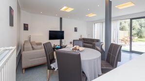 A modern living room with a sofa, chairs, a dining table, and a TV. - Charming 2-bedroom villa in brilliant Merelbeke-Melle with AC (Merelbeke-Melle)