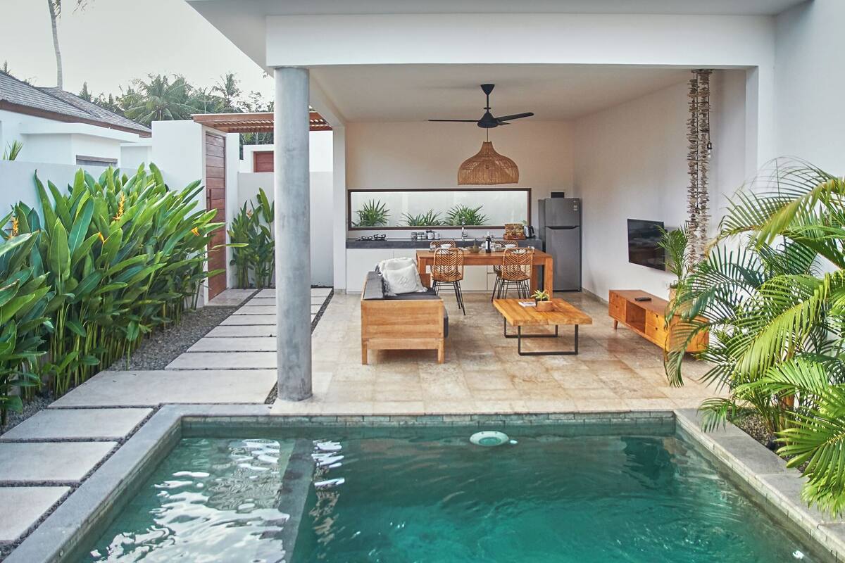 A modern outdoor living area with a pool, dining space, and kitchen.