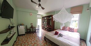A bedroom with a bed, a desk, a chair, a wardrobe, a ceiling fan, and a window with a curtain. - Cozy Apartment Kitchen 1 (Sala Dan)