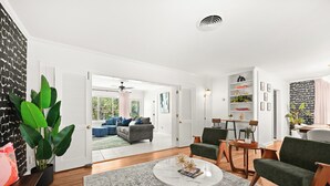 A spacious living room with a large coffee table, comfortable seating, and a view to the outside. - Stylish Home Near Stadium | Hot Tub, BBQ, Fire Pit (Baton Rouge)