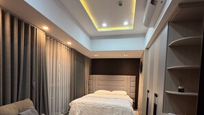 A modern bedroom with a bed, a sofa, a desk, and a wardrobe.