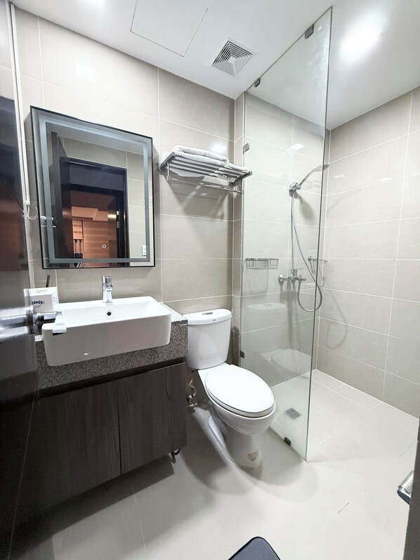 Un baño moderno con cabina de ducha de vidrio, un lavamanos blanco y un inodoro.