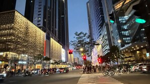A city street at night with tall buildings, a crosswalk, and traffic lights.