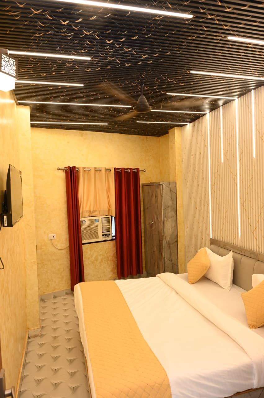 Una habitación de hotel con una cama, un ventilador de techo, una ventana con cortinas y un televisor montado en la pared.