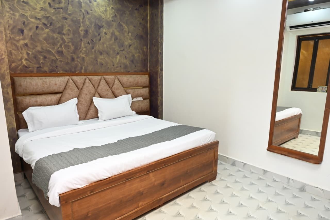 A bedroom with a wooden bed, white bedding, and a large mirror on the wall.