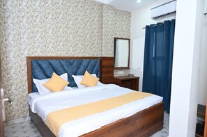 A bedroom with a wooden bed, a mirror, and a patterned wallpaper. - Sawaria Residency (Varanasi)
