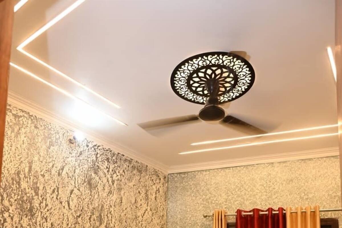 Quarto com cama, ventilador de teto, janela com cortinas e ar condicionado.
